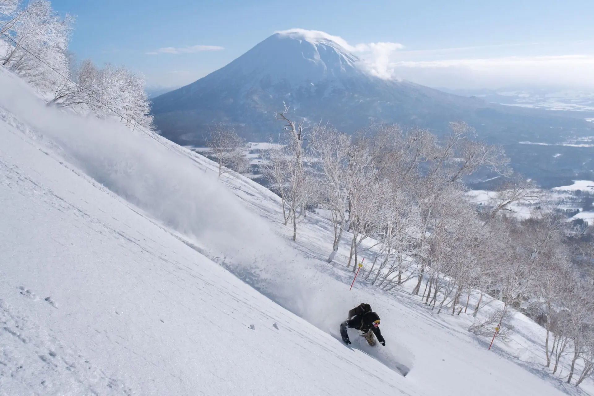 Snowboarder carving powder with Mt. Yotei in the distance